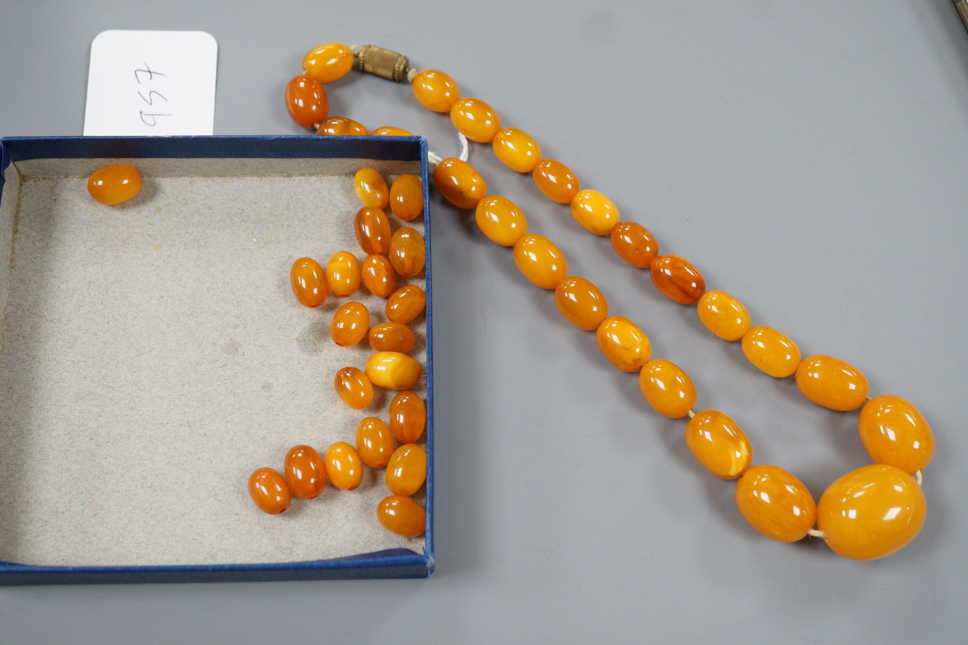 A single strand graduated oval amber bead necklace, 42cm, gross 49 grams and assorted loose amber beads, 15 grams.